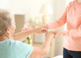 Old and young women holding hands on blurred background